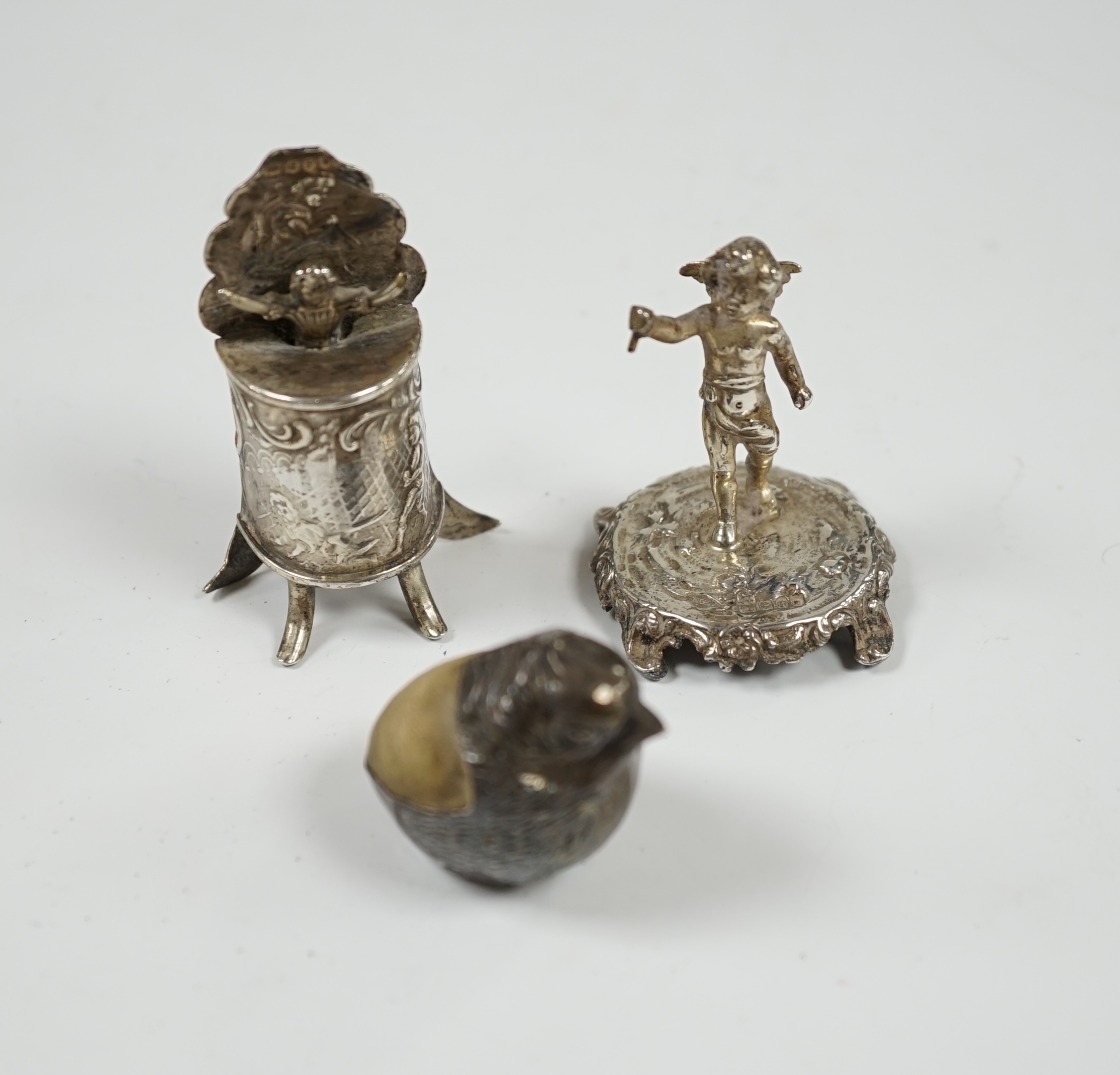 An Edwardian silver mounted 'hatching chick' pin cushion, by Sampson Mordan & Co, Chester, 1908, 29mm, together with two miniature silver groups with import marks. Condition - fair